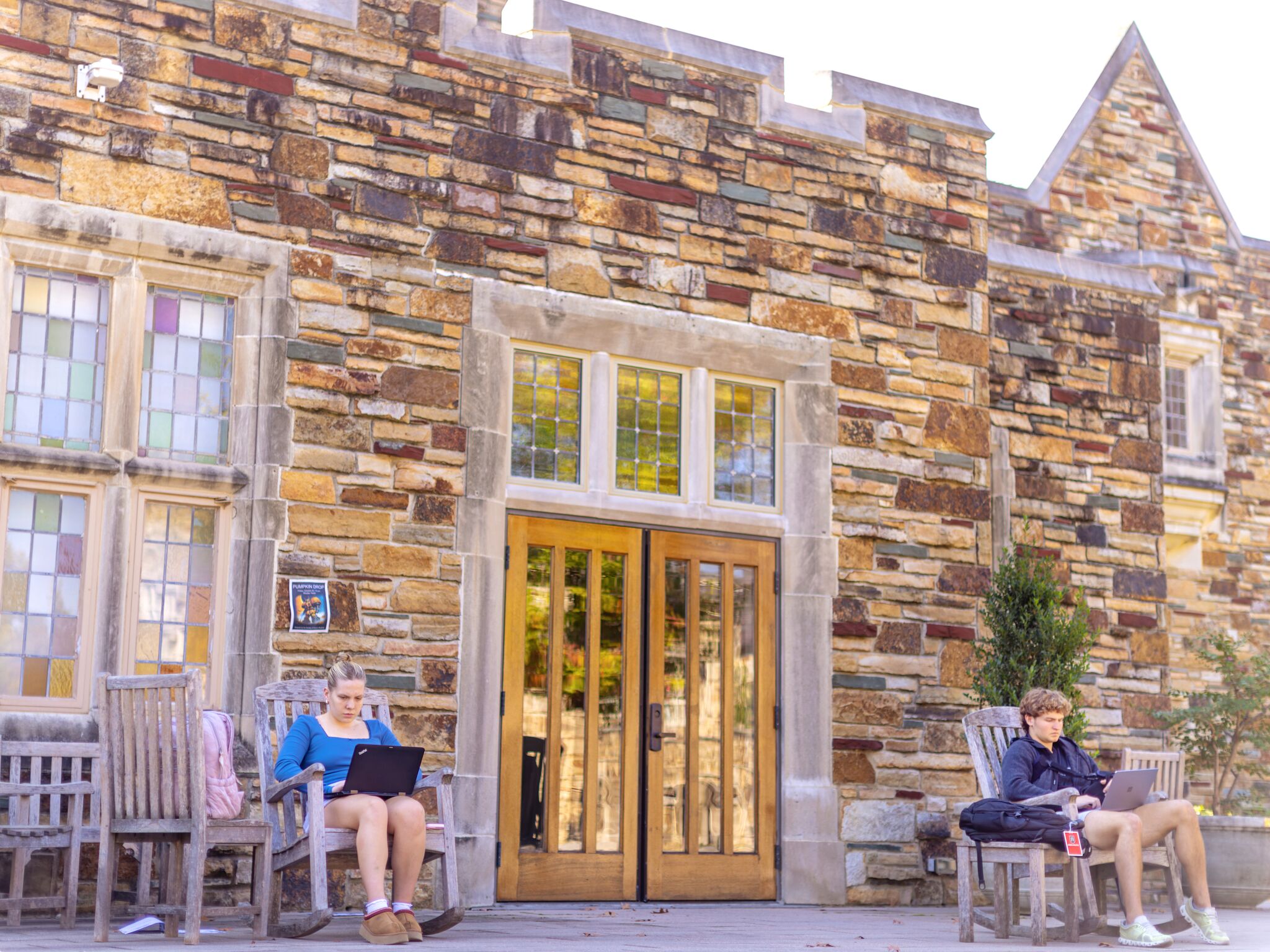 Students study on the outside patio of a stone Gothic building